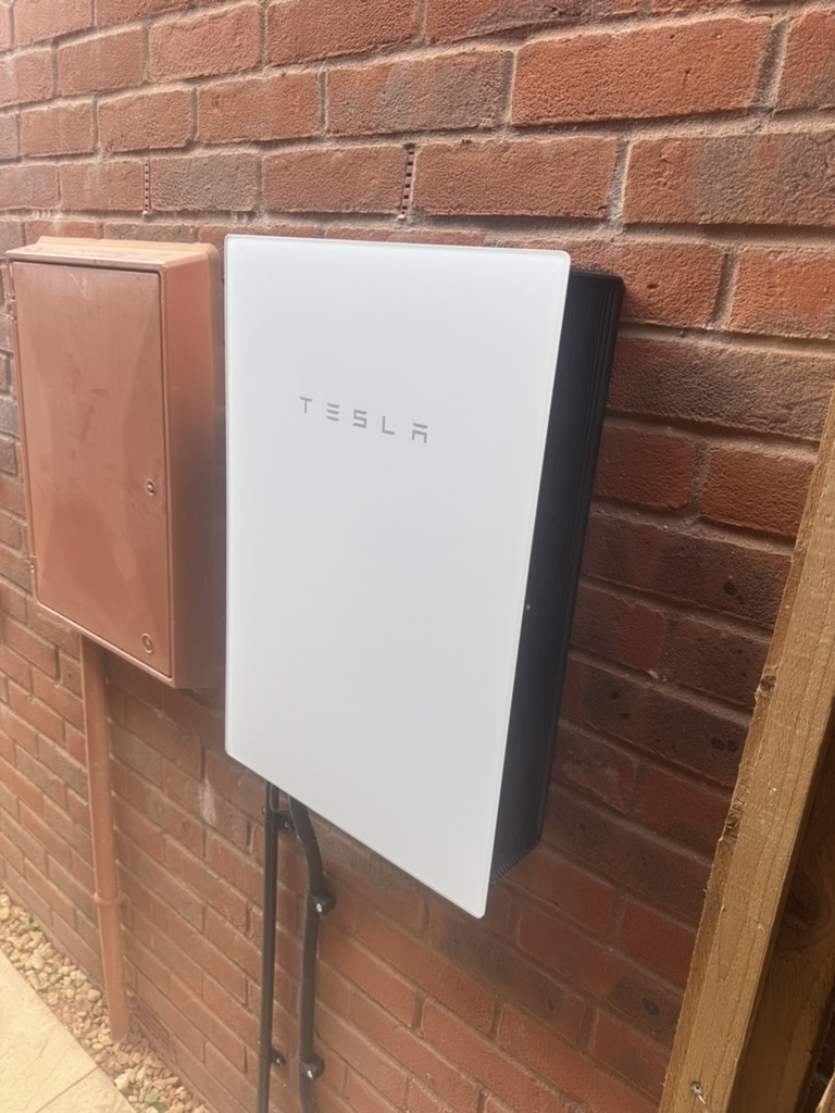 Wall-mounted Tesla equipment on an exterior brick wall with neatly routed cabling