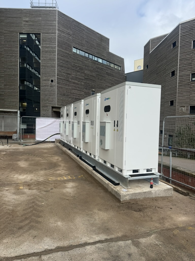 Side view of a row of large battery storage cabinets on a raised installation base