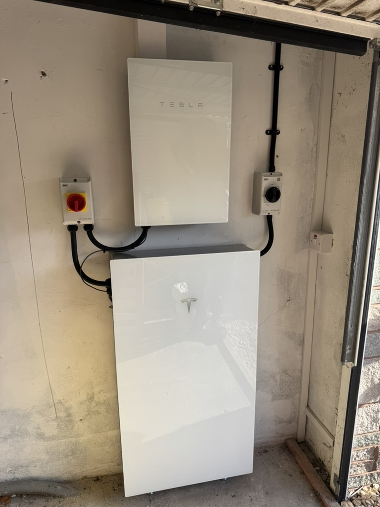 Tesla home battery and wall-mounted equipment installed inside a garage with electrical isolators